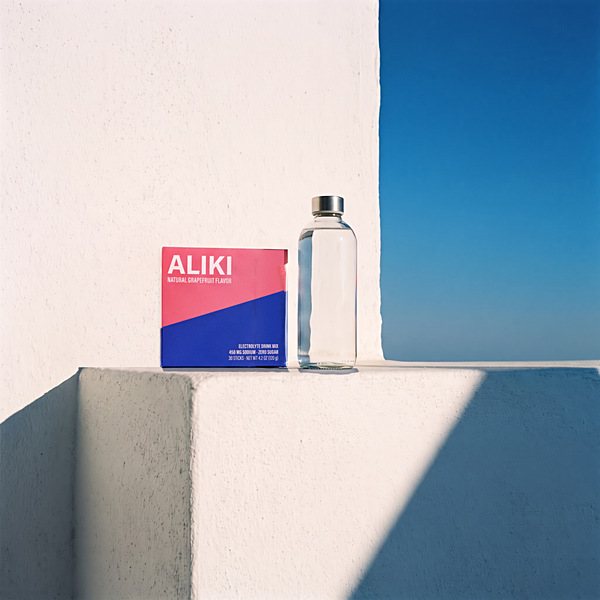 The same ledge at 6 pm, evening shade across the ledge beside the ALIKI carton and the bottle