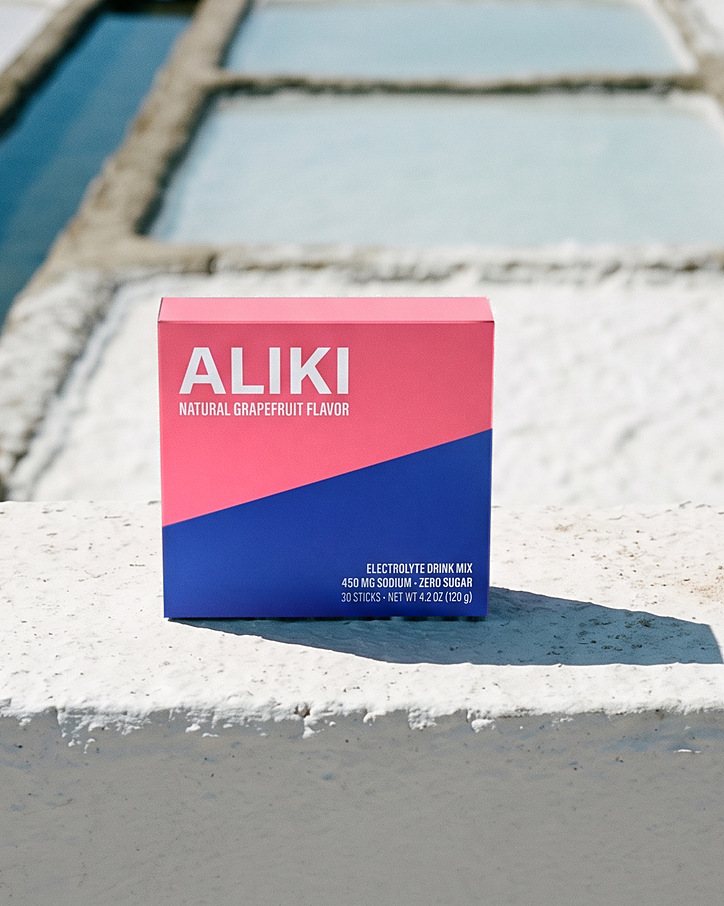 ALIKI Grapefruit carton on a whitewashed salt-pan dike, salt pans behind it in hard sun
