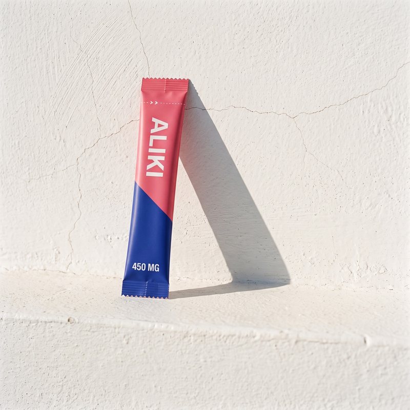 One ALIKI stick, 450 mg, leaning on a whitewashed wall in hard sun