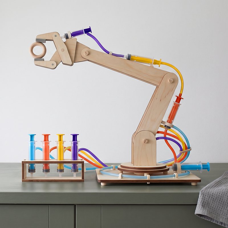 The Fulcra arm by a window, four colored water lines, a wooden ring in the gripper