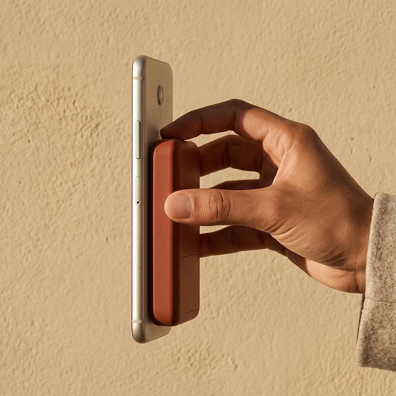 Hand holding the Kelda 37 pack, a phone beside it on the magnets