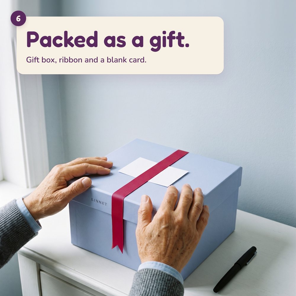 AI-generated hands resting on the Linnet gift box, a blank card under the raspberry ribbon