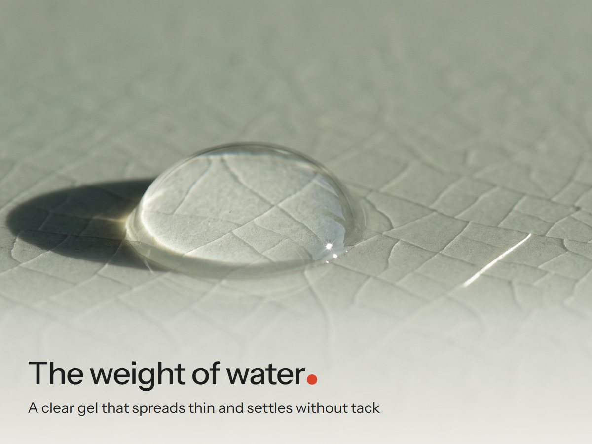 One clear serum drop on a crackle-glaze celadon tile in low side light, its shadow long on the glaze
