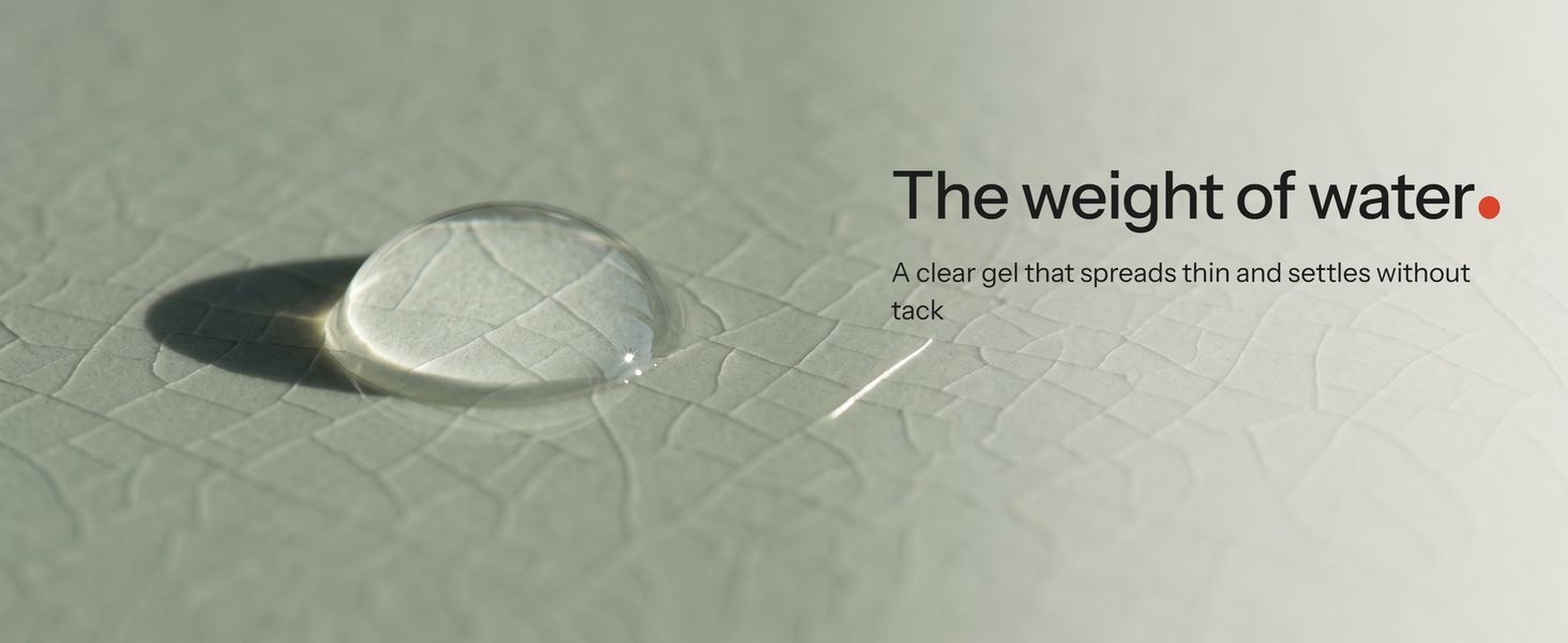 One clear serum drop on a crackle-glaze celadon tile in low side light, its shadow long on the glaze