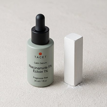 Tacet Calm Serum bottle capped beside a chalk block on pale stone