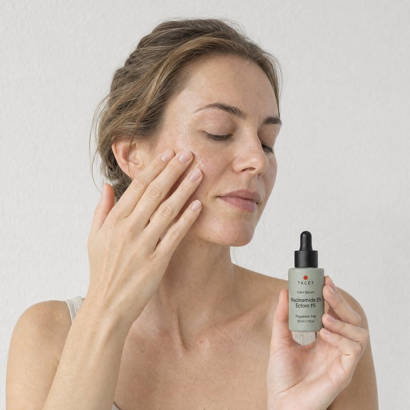 Woman pressing the serum into her cheek, bottle in her other hand