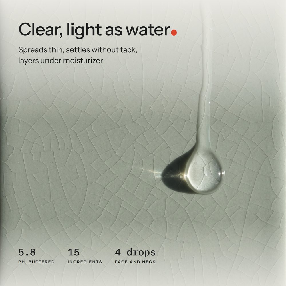 Macro of one clear serum drop sliding down a crackle-glaze celadon tile in low side light