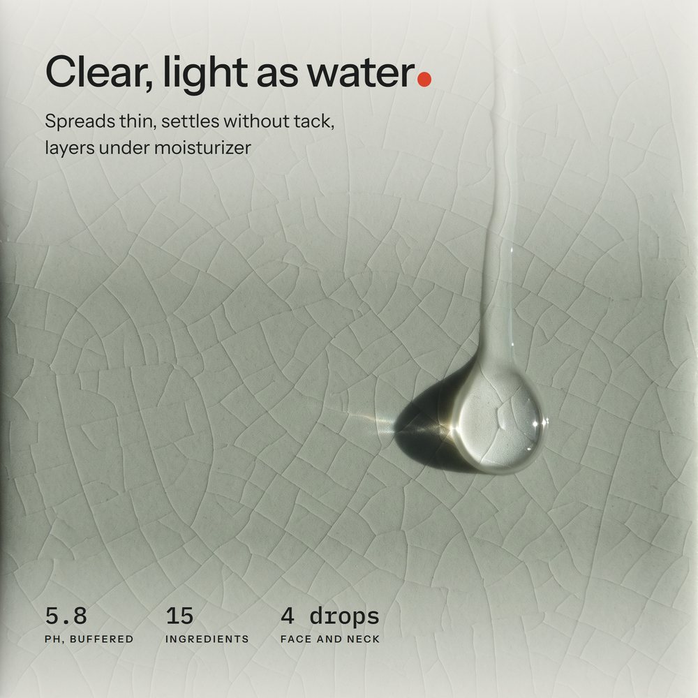 Macro of one clear serum drop sliding down a crackle-glaze celadon tile in low side light