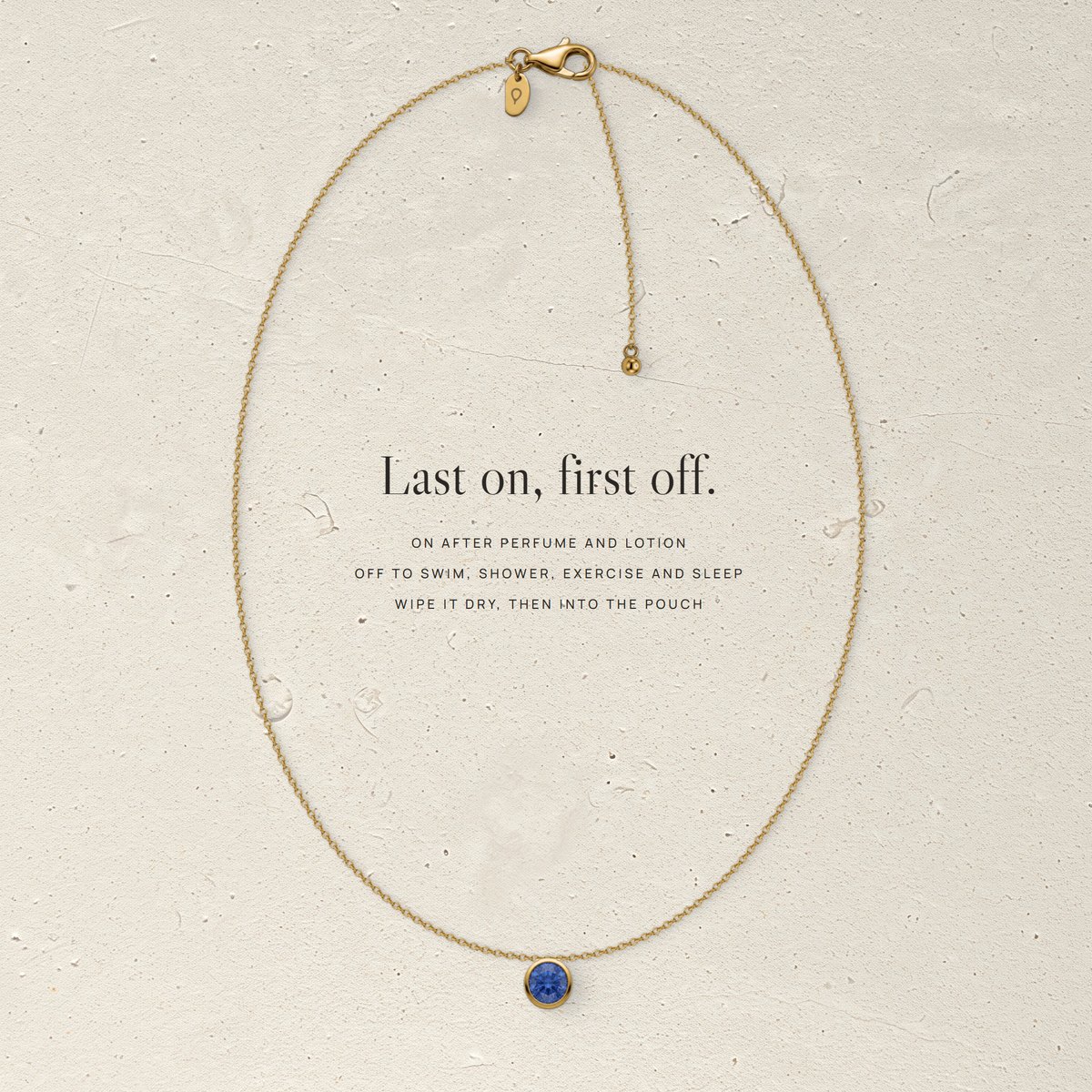 Corund vermeil necklace laid flat on pale limestone, with three care steps