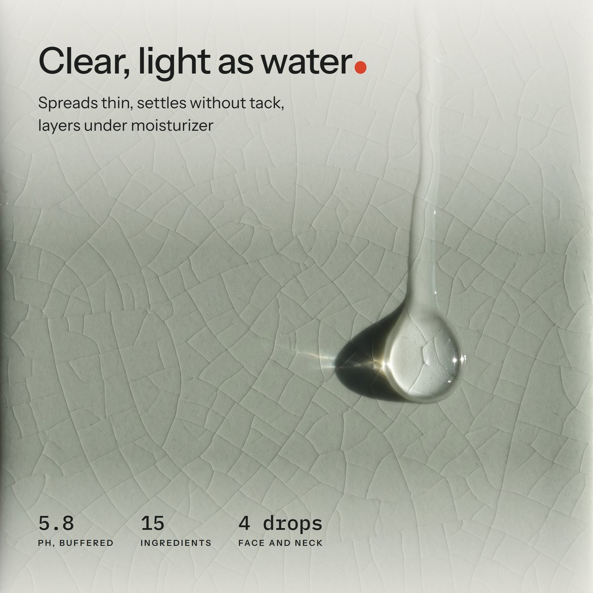 Macro of one clear serum drop sliding down a crackle-glaze celadon tile in low side light